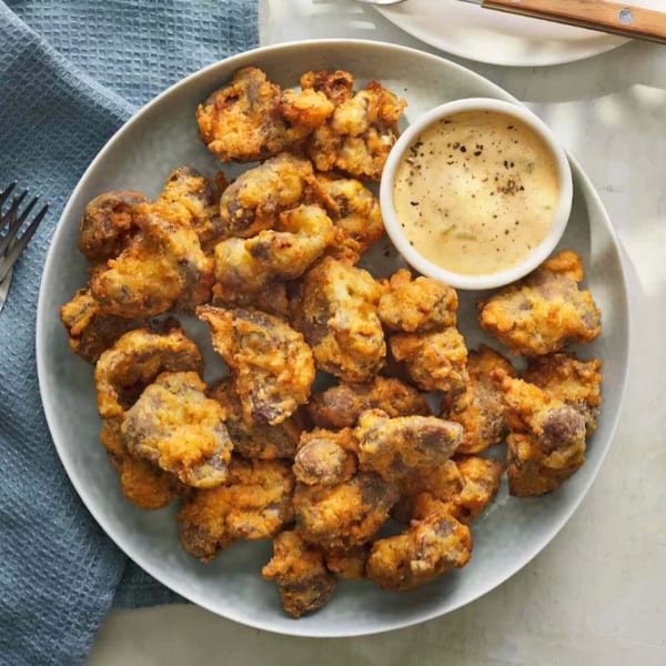 A plate of golden-brown fried seafood pieces with a side of creamy dipping sauce.