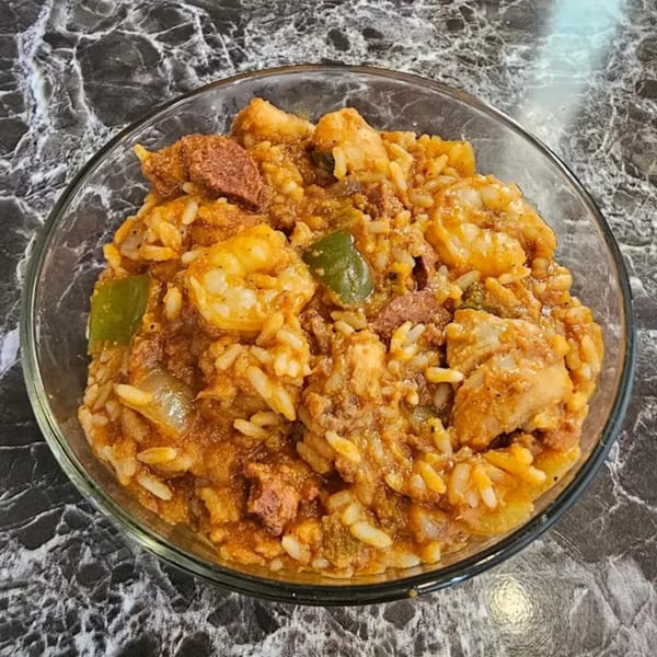 A clear bowl of Ray's Chicken & Fish jambalaya with shrimp, sausage, rice, and vegetables.